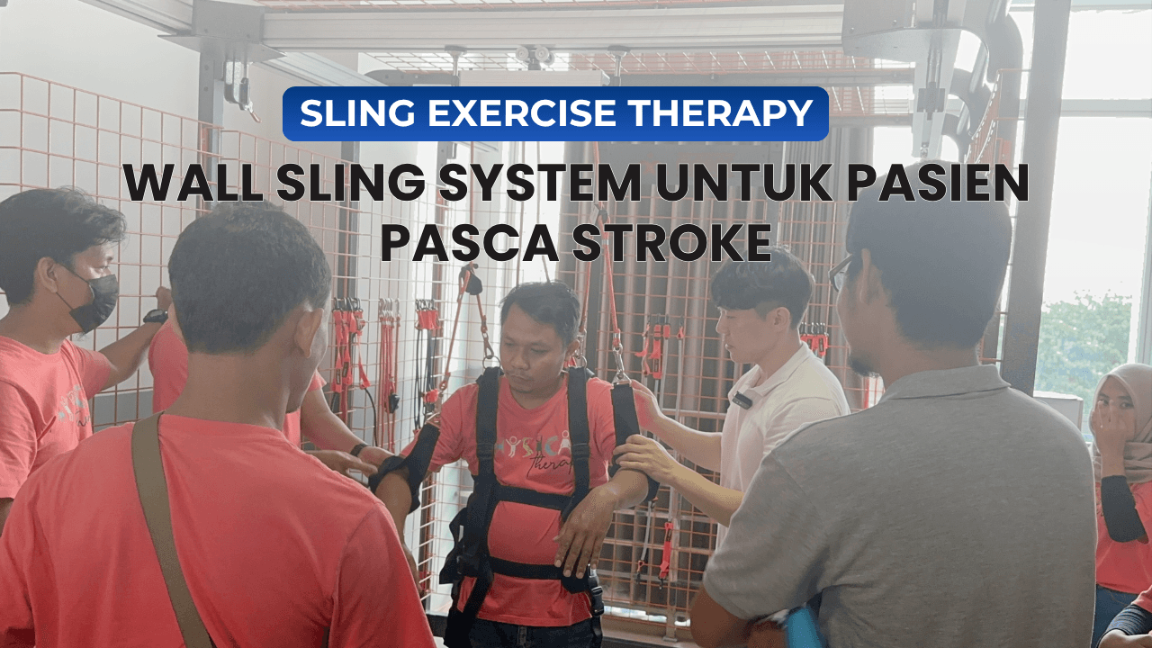 Seorang peserta terapi sedang mencoba Wall Sling System dengan bantuan fisioterapis dan peserta lainnya untuk latihan stabilitas dan keseimbangan tubuh.